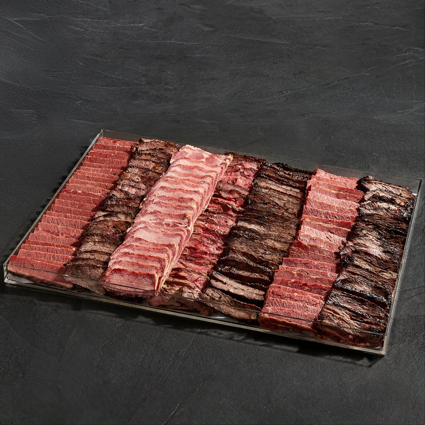 Gourmet Cooked Kosher Meat Board featuring sliced brisket, roast beef, and deli meats on a clear acrylic tray from Satmar Meats.